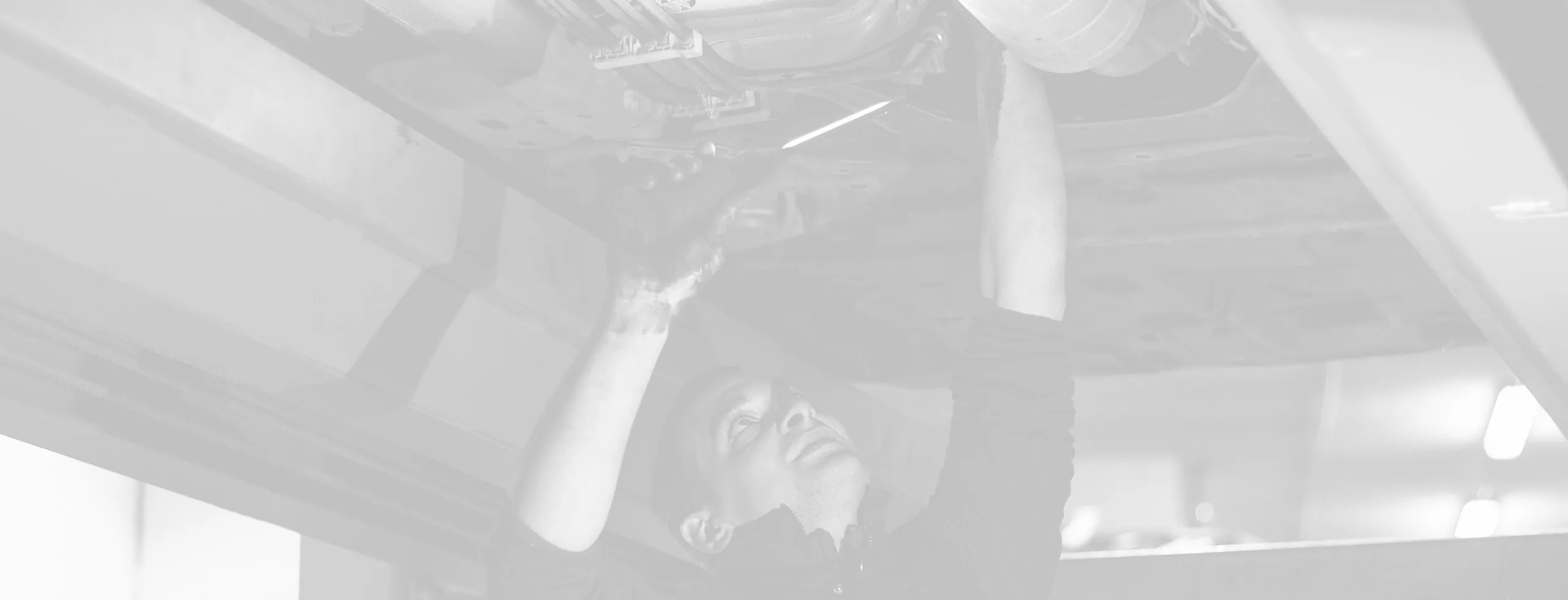 Mechanic working under a vehicle in garage.